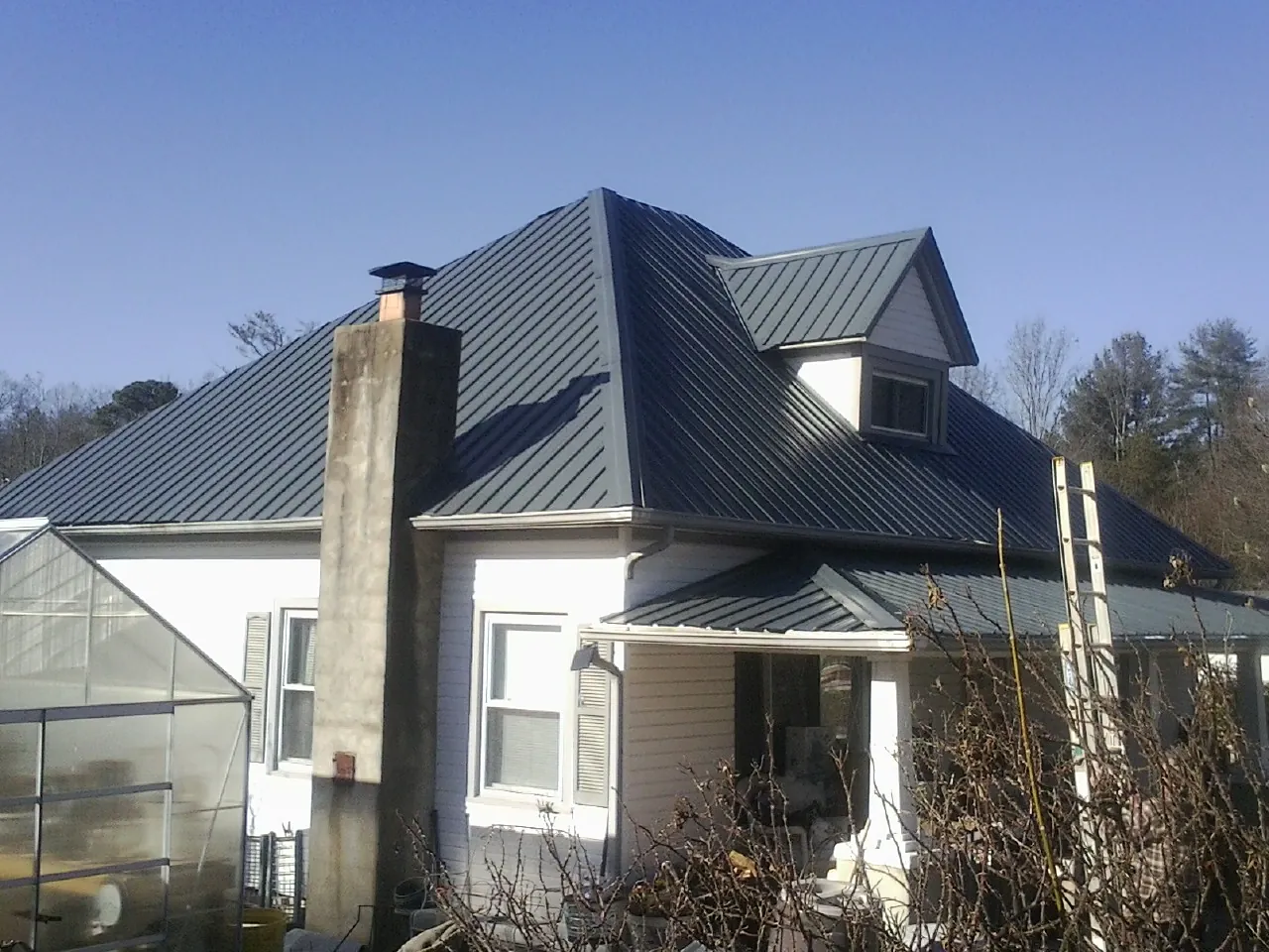 Dark blue standing seam metal roof on a white farmhouse with dormer — Slate & Tile Roof Repair by Roofing Brothers in Lewisburg