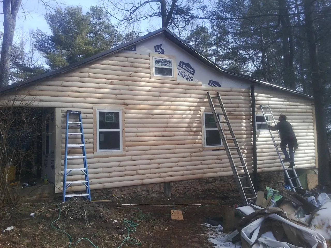Ladders set against fresh log siding during an exterior remodel in Lewisburg