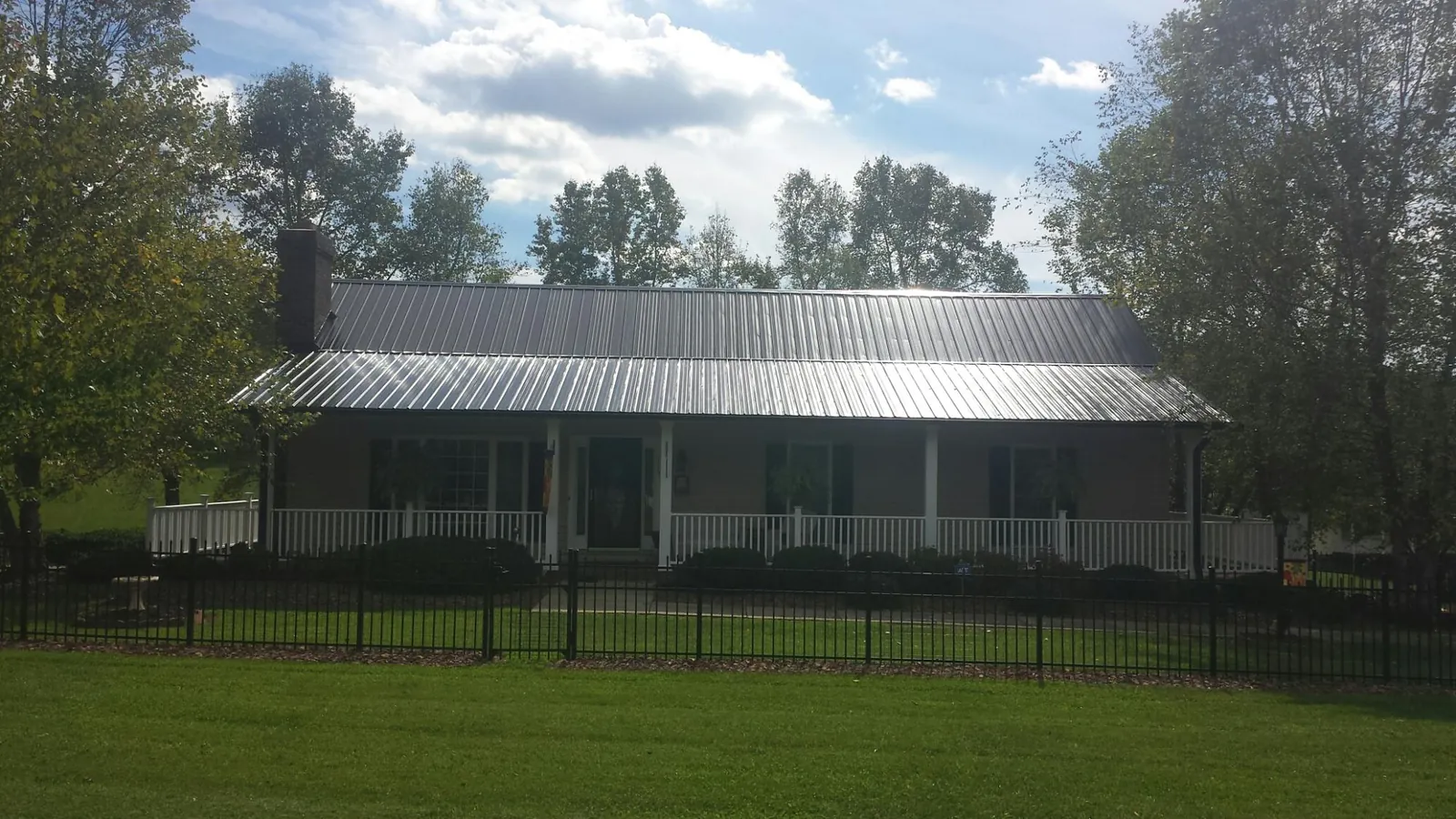 Gray metal roof on a brick ranch with a full width front porch — Gutter Guard Installation work by our crew in Lewisburg