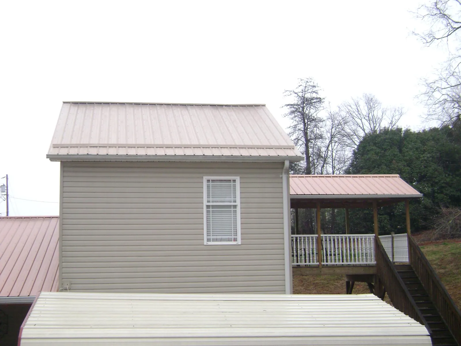 Tan metal roofs on a two story addition and attached porch, from a Roof Replacement job in Lewisburg
