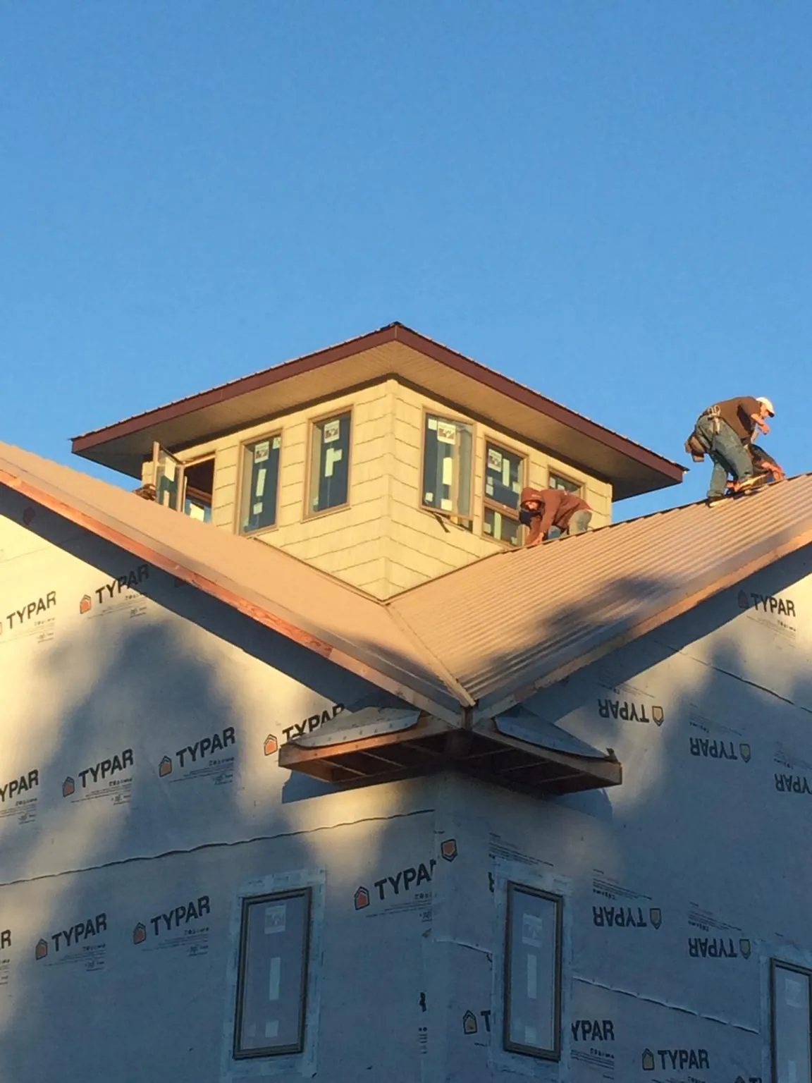 Roofers working around a rooftop cupola on a new metal roof at sunset — Roof Waterproofing in Lewisburg by Roofing Brothers